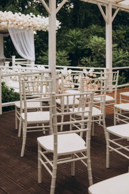 Güzel bir ahşap güverte boyunca dizilmiş saf beyaz sandalyeler davetkar bir atmosfer yaratıyor.