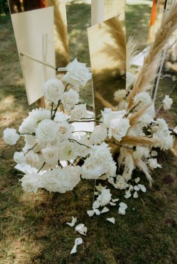 Güzel bir demet beyaz çiçek, zarif bir şekilde, yakınlardaki zarif bir aynanın önünde, yere yerleştirilmiştir.