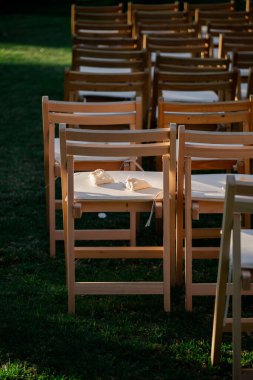 Güzel bir sıra ahşap katlanır sandalye zarif bir şekilde yemyeşil bir alana yerleştirilmiş, davetkar bir açık hava ortamı yaratıyor.
