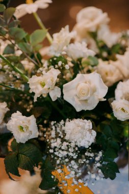 Bu detaylı yakın plan resimde, ağzına kadar narin beyaz çiçeklerle dolu çok güzel bir vazo görebiliyoruz.