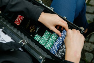 Bir insan kendinden emin bir şekilde ağzına kadar canlı ve renkli poker fişleriyle dolu sağlam bir çanta tutuyor.