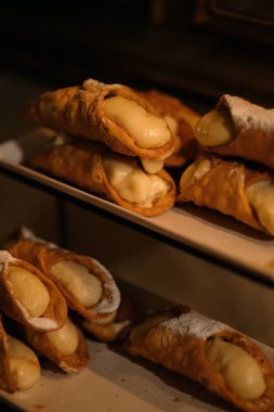Güzelce hazırlanmış lezzetli bir canoli tepsisi, üzerine tatlı ve sunum için cömert bir pudra şekeri katılmış.