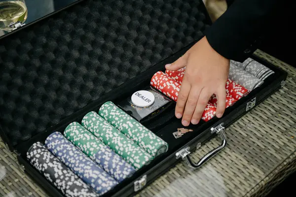 Bir kişi dikkatlice çantanın içine çeşitli renkli poker çipleri yerleştiriyor. Düzenli ve güvenli olduğundan emin olmak için.
