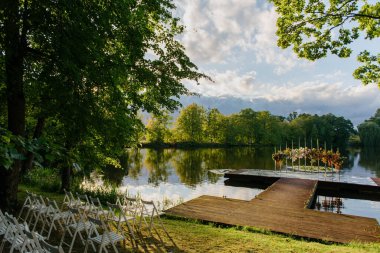 Güzel bir sıra sandalye, gün boyunca dingin bir gölün yanındaki ahşap rıhtımda mükemmel bir şekilde dizilmiştir.