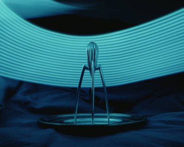 Sulu Salif narenciye suyu var. Şu anda tabakta duruyor. Arkasında mavi bir ışık var.