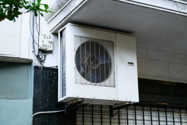 A white air conditioning unit is securely mounted on the side of a residential building, contributing to the overall facade and comfort clipart