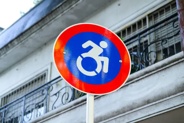 Üzerinde tekerlekli sandalyedeki birinin açık bir ikonu olan canlı kırmızı ve mavi bir tabela bireyler için ulaşılabilirlik özelliklerini gösteriyor.