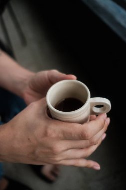 Bir insan elinde sıcak bir fincan taze kahve tutarken rahatlamanın ve rahatlamanın tadını çıkarıyor.