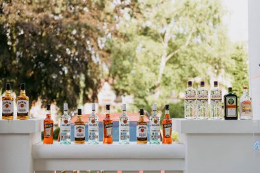 Geniş çaplı bir şekilde, çeşitli içki şişeleri düzenli bir şekilde cilalı bir masaya dizilir ve görsel olarak çekici bir görüntü yaratır.