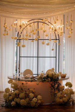 Çok güzel düzenlenmiş bir masa var. Canlı çiçekler ve titreyen mumlarla süslenmiş. Zarifçe güzel bir pencerenin önüne konmuş.