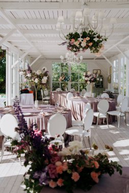 Geniş bir odada, düşünceli bir şekilde düzenlenmiş birkaç masa ve sandalye var ve masalardan birinde belirgin bir şekilde sergilenen çok güzel bir vazo çiçek.