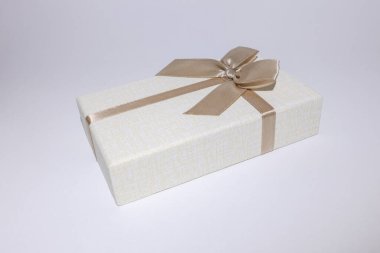 Kahverengi fiyonklu bej bir hediye kutusu, beyaz arka planda izole edilmiş. Stok fotoğrafı