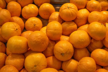 Parlak, taze portakal yığını, canlı turuncu renkler ve desenli deri sergiliyor. Görüntü, meyvenin tazeliğini ve doğal çekiciliğini vurguluyor, gıda piyasaları veya sağlıklı yaşam tarzları için mükemmel..