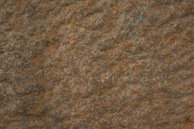 Close-up of a natural stone texture with earthy tones of orange and gray. Ideal for backgrounds, designs, or architectural projects requiring a raw, organic surface. clipart