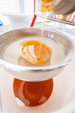 Pürüzsüz ve kremalı Altın Bal Filtreleme Sieve 'ine akıyor