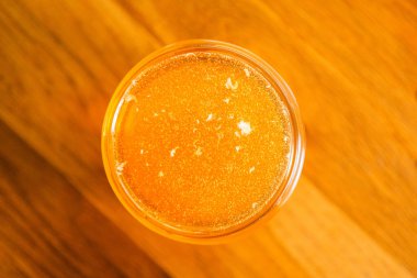 Top View of Sweet Golden Bee Bal with Bubbles Taze toplanmış Tahta bir yüzeye yakın duruyor