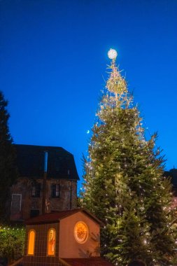 Uzun bir Noel ağacının üzerindeki parlak ışıklar Hilal bir ay ve küçük bir şehirde kayan küçük bir yıldızla geceyi aydınlatan bir yıldızla tepesinde.