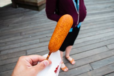 Düz kahverengi Corndog Tahta İskeledeki Bir El Tutun