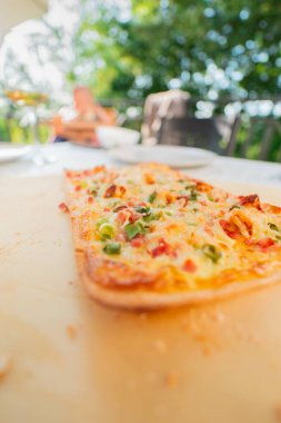 Taze Fransız Tarte Flambe Flammekueche yanında Creme Fraiche Peynirli Pastırma Küpü ve Tahta Tablet Tabletinde Taze Soğan Kapatın