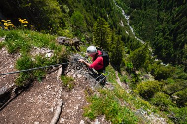 Sport Climbing a Steel Wire of a Via Ferrata 'nın Dik Kayalık Uçurumunda Tırmanıyor