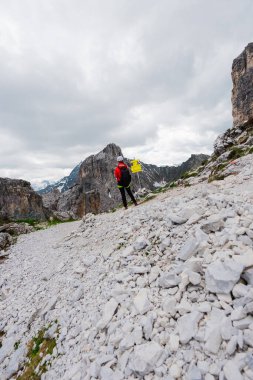 Bir dağ yolunun çatalında duran yürüyüşçü Bulutlu bir günde yol işaretine bakıyor.