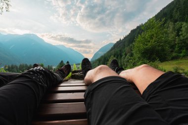 Resting Hiker on a Hike Bench in Nature in a Mountain Landscape Looking at the Clouds clipart