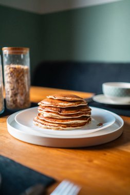 Tahta bir kahvaltı masasında duran beyaz tabakta duran güzel krep yığını