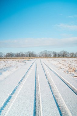 Soğuk Buzlu Kar 'a yerleştirilmiş Lastik İzleri ile Bir Kış Manzarasında Alan Yolu