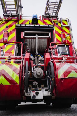 Büyük bir itfaiye aracının tam teçhizatlı arkasında su hortumları söndürme ekipmanları ve merdivenleri operasyona hazır.
