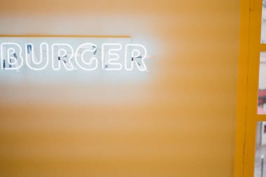 Sarı Duvarda Burger Metni olan Beyaz Neon Işık Tüp