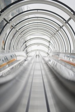 Dışarıdaki Güneş 'e Açılan Parlak Cam Tünel' de Yürüyen Yürüyen Yürüyen Bir Yürüteç Görüntüsünü Kapat