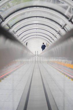 Kamu alanındaki Cam Tünel 'e simetrik olarak bölünmüş bir yürüyen merdivenin rayları