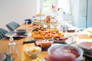 Çok güzel hazırlanmış brunch masası, çeşitli lezzetli ve tatlı yemekler, sıcak güneş ışığıyla yıkanmış. Yemek, ev toplantıları ve aşçılık ilhamları için mükemmel..
