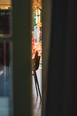 Dar bir aralıktan görünen zarif sandalyeli şık bir iç mekan, rahat, rahat bir ortam için ışık ve gölgelerin etkileşimini vurguluyor..