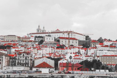 Lizbon 'un panoramik manzarasında büyüleyici kırmızı çatılar, tarihi binalar ve ikonik mimari bulutlu gökyüzü altında Portekiz' in canlı başkentinin özünü yakalıyor.