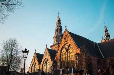 Karmaşık vitray pencereleri olan Gotik mimarisi olan güzel tarihi bir kilise, açık mavi gökyüzüne karşı duruyor ve şehir ortamında klasik Avrupa tasarım unsurları sergiliyor..