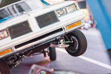 Klasik bir Amerikan arabası, hidrolik sistemini ve klasik çekiciliğini ön plana çıkaran bir şehir caddesine çarpıcı bir şekilde dayanır. Arka plandaki şehir ışıkları heyecan ve tarz katıyor..