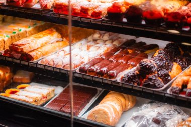 A tantalizing display of diverse pastries and desserts in a bakery shop, featuring cannoli, eclairs, cookies, and cakes. Captures the essence of sweet indulgence for pastry enthusiasts. clipart