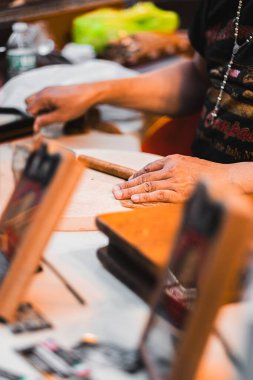 Skilled artisan crafts a traditional cigar in a bustling marketplace, emphasizing the art of cigar making. Highlighting traditional craftsmanship and the cultural richness of artisan markets clipart