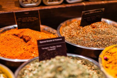 Metal kaselerde çeşitli baharat ve bitkiler, Cajun ve özel karışımlar sergileniyor. Bu pazar görüntüsü lezzetli yemek pişirme ve aşçılık araştırmalarında kullanılan zengin renkleri ve dokuları vurgular