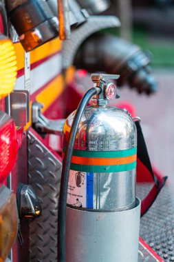 Bir itfaiye aracına monte edilmiş bir yangın söndürücünün yakın plan görüntüsü, kentsel bir çevrede acil durum hazırlığını ve güvenlik ekipmanlarını vurguluyor.