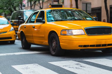 Hızlı şehir yaşamını ve ikonik ulaşımı temsil eden hareketli şehir sokaklarından geçen sarı taksi. Hareket halinde yakalanan bu görüntü, şehir yaşamının canlı enerjisini ve özünü vurgular.