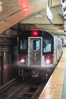 Loş bir yeraltı istasyonuna ulaşan metro treni, günlük gidiş-dönüş sırasında kentsel yaşamı ve toplu taşımayı ön plana çıkarıyor. Platformda yolcular için sarı bir güvenlik hattı yer alıyor..