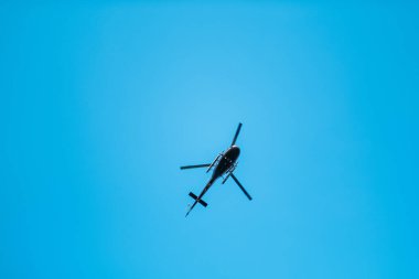 Açık mavi gökyüzünde uçan bir helikopterin silueti özgürlük, macera ve ulaşımı temsil ediyor. Havacılık ve keşfin özünü havadan bir perspektiften yakalar..