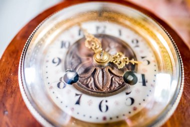 A detailed view of an antique clock showcasing ornate brass elements, Roman numerals, and craftsmanship. The clock's design reflects elegance and historical significance, set on a polished wooden base clipart