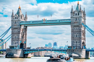 Londra 'daki İkonik Kule Köprüsü güneşli gökyüzü ve kabarık bulutların altındaki Thames Nehri' ni kaplayarak olağanüstü mimarisini ve tarihsel önemini vurgular. Şehrin mükemmel bir sembolü.