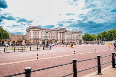 Buckingham Sarayı 'nı ziyaret eden turistler Londra' nın zengin tarihi ve kültürünü sergilediler. Tarihi mimari, bulutlarla dolu bir gökyüzünün altında gururla duruyor. Resimli bir şehir manzarası yaratıyor.
