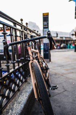 Bir bisiklet hareketli bir şehir caddesinde çitlere dayanır, canlı şehir manzarasını ve modern şehir yaşamında bisiklet sürmenin artan popülerliğini resmeder..