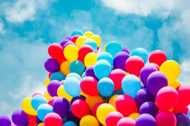 Parlak mavi gökyüzünde yüzen renkli balonlardan oluşan canlı bir çeşitlilik neşe, kutlama ve canlı kutlamalar hissi uyandırıyor. Mutluluk ve özgürlük teması için mükemmel..