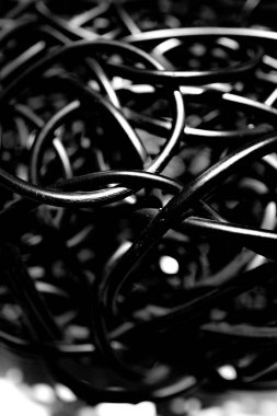 Black and white abstract photograph of tangled black cables creates an artistic composition. Dynamic curves, and interwoven lines, ideal for modern art and design inspiration clipart